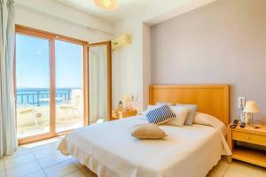 a bedroom with a bed with a view of the ocean at Triton Authentic Cretan Hotel in Tsoútsouros