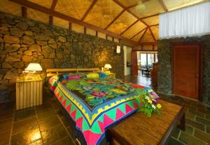 una camera con un letto colorato in una parete in pietra di Coconuts Beach Club Resort and Spa a Fausaga