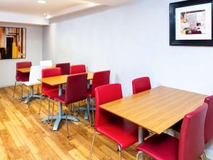 una sala de conferencias con mesas de madera y sillas rojas en ibis budget Burton Upon Trent Central, en Burton upon Trent