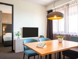 Zimmer mit einem Tisch und Stühlen sowie einem Schlafzimmer in der Unterkunft Adagio Amsterdam City South in Amstelveen