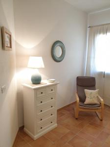 una camera da letto con cassettiera, lampada e sedia di Capo Figari 9, appartamento a Golfo Aranci a Golfo Aranci