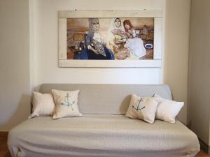 a couch with pillows and a painting on the wall at Capo Figari 9, appartamento a Golfo Aranci in Golfo Aranci