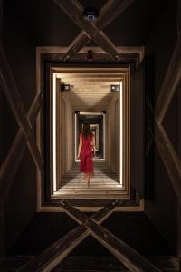a woman in a red dress walking down a corridor at Hotel Bohinj in Bohinj