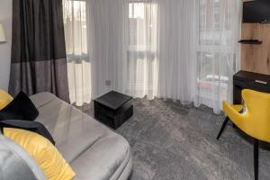 salon z kanapą i żółtym krzesłem w obiekcie Arany Apartman Miskolc w Miszkolcu