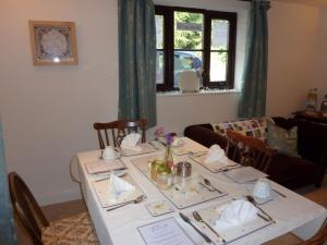 Shepherds Row Bed and Breakfast في West Haddon: طاولة طعام مع طاولة قماش بيضاء