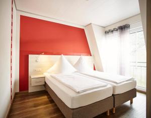 a bedroom with a large bed with a red wall at Weinhaus Lenz in Briedern