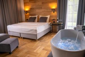 1 dormitorio con cama y bañera en Caryńska Resort & SPA, en Lutowiska