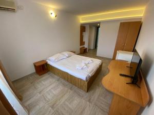 a small bedroom with a bed and a table at Hotel Gorj in Târgu Jiu