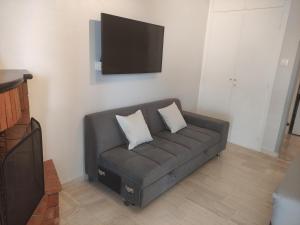 a living room with a couch with a tv on the wall at Studio Sunset in Platanidia