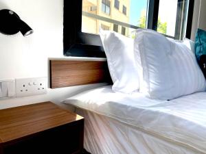 a bedroom with a bed with white sheets and a window at Urban Habitat Executive Suites in Nicosia