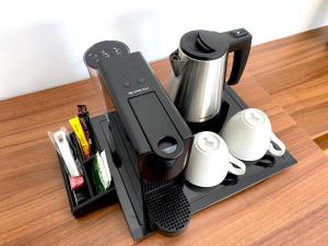 a black coffee maker and cups on a table at Urban Habitat Executive Suites in Nicosia