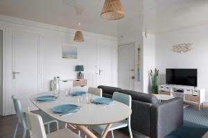 sala de estar con mesa blanca y sofá en Le Pouliguen vous accueille pour un sejour dans ce bel appartement en Le Pouliguen