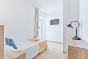 ein Schlafzimmer mit einem Bett, einem Schreibtisch und einer Lampe in der Unterkunft Suncoast Ibiza Hotel - Adults Only - in Ibiza-Stadt