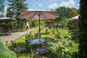 einen Tisch und Stühle mit Sonnenschirm und Spielplatz in der Unterkunft Centrum Ulan Spa in Bytów