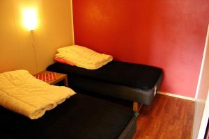 two twin beds in a room with a red wall at Sildpollnes Sjøcamp in Vestpollen