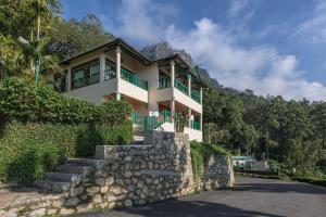 a house on a hill with a stone wall at Club Mahindra Munnar in Chinnakanal