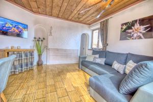 salon z niebieską kanapą i drewnianym sufitem w obiekcie Haus Kitzsteinhorn 7 - by Alpen Apartments w Kaprunie