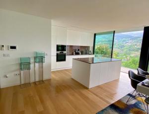 Eine Küche mit weißen Schränken und einer Theke mit Hockern in der Unterkunft Alynes 2 Villa individuelle, piscine, spa, sauna panoramique in Ventosa