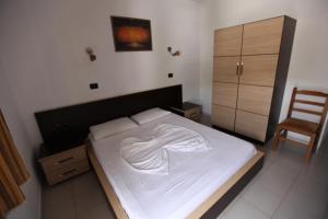a bedroom with a large white bed with a chair at Hotel Colosseo in Vlorë