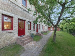 a brick building with a red door and a tree at Scheune am Loppiner See in Jabel