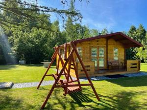 une cabane en rondins avec balançoire dans une cour dans l'établissement Domek nad Solina z klimatyzacją, à Uherce Mineralne
