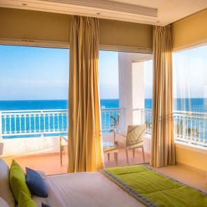 a bedroom with a bed and a balcony with the ocean at Hotel Bel Azur Thalasso & Bungalows in Hammamet