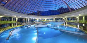 a large indoor swimming pool with a glass dome at Villa Aina Boutique Hotel in Laško