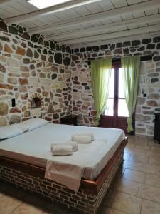 a bedroom with a large bed in a stone wall at Athina EcoFarm in Ancient Epidauros