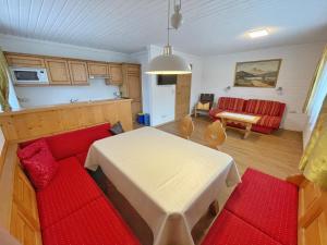 a living room with a white table and a red couch at Pension Erlhof in Saalfelden am Steinernen Meer