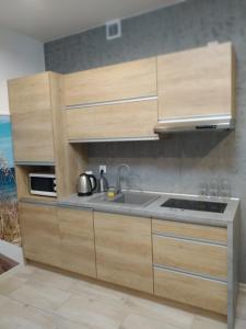 kuchnia z drewnianymi szafkami i zlewem w obiekcie Apartamenty Bulwar Nadmorski, Ustka w Ustce