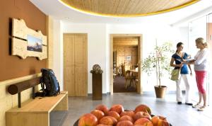 deux femmes debout dans une pièce avec une pile de pommes dans l'établissement Martina Breakfast Lodge, à Castelrotto
