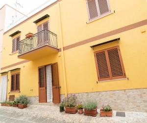 um edifício amarelo com vasos de plantas em frente em Via San Bartolomeo primo piano e terrazzo em Ustica