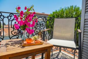 a table and a chair on a balcony with pink flowers at PROVENCE MANSİON ALAÇATI in Alacati