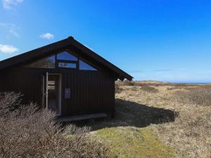 Un pequeño edificio negro situado en la cima de una colina. en 4 person holiday home in Bindslev, en Bindslev 28 fotos más