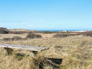 un banco de madera sentado en un campo de hierba alta en 4 person holiday home in Bindslev, en Bindslev