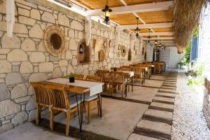 a restaurant with tables and chairs and a stone wall at PROVENCE MANSİON ALAÇATI in Alacati