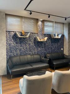 a living room with a leather couch and chairs at Carpe Diem Apartments-Hotel in Sh&euml;ngjin