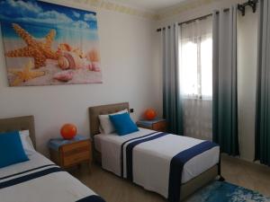 a bedroom with two beds with blue and white sheets at SARA HOUSE NADOR in Nador