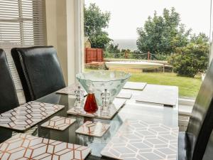 uma mesa de vidro com cadeiras e uma taça de vidro sobre ela em Llys Madoc, Basement Apartment em Penmaen-mawr