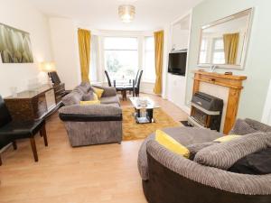 uma sala de estar com dois sofás e uma lareira em Llys Madoc, Basement Apartment em Penmaen-mawr