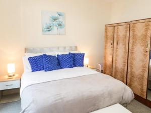een slaapkamer met een groot bed met blauwe kussens bij Llys Madoc, Basement Apartment in Penmaen-mawr