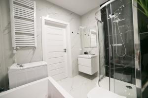 een witte badkamer met een douche en een wastafel bij Oxygen apartament nr 1 in Mielec