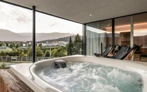 Bellevue Bruneck - Suites & Lofts في برونيكو: حوض استحمام في منزل مع نوافذ