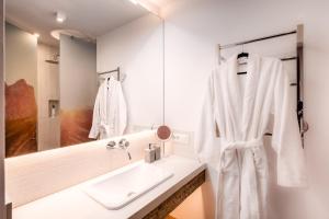a white bathroom with a sink and a mirror at Bellevue Bruneck - Suites & Lofts in Brunico