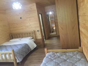 two beds in a room with wooden walls at Guesthouse Demushi in Valbonë