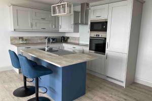 una cucina con armadi bianchi e un'isola blu con lavandino di The Loft Cottage a Glastry