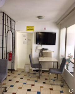 Zimmer mit 2 Stühlen, einem Tisch und einem TV in der Unterkunft Neureut in Karlsruhe