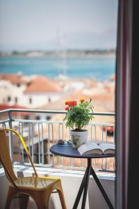 a table with a book and a plant on a balcony at Porto Bello Nafplio in Nafplio