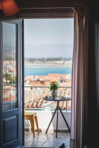 a balcony with a table and a view of the water at Porto Bello Nafplio in Nafplio