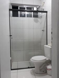 a bathroom with a toilet and a glass shower at Kit Ocian in Praia Grande